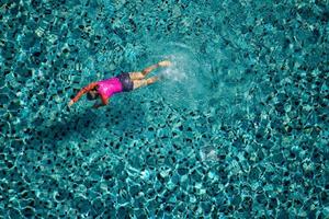 mulher nadar na piscina do hotel. vista de cima. foto