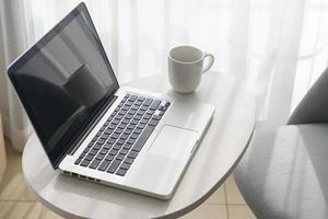 laptop e xícara de café na mesa e cadeira no quarto foto