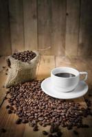xícara de café preto e grãos de café foto