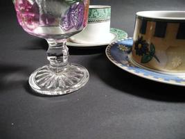 xícara de chá, xícara de café e vidro estampado de frutas transparente cheio de água mineral em um fundo preto. foto