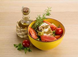 salada grega em uma tigela sobre fundo de madeira foto