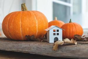 fundo outonal. casa de brinquedo e abóbora em fundo de madeira. espaço de cópia de banner de ação de graças. humor hygge, conceito de mudança de estações. olá outono com festa de halloween em família. foto