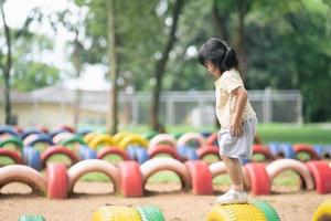 menina asiática bonitinha jogando amarelinha ao ar livre. jogo de atividade  engraçado para crianças no playground