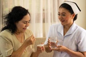 enfermeira tomando pílulas para paciente do sexo feminino no quarto. foto