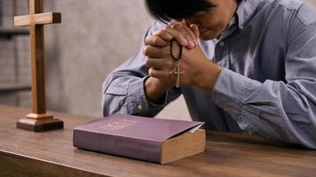 um jovem cristão asiático orando a jesus cristo em uma igreja. foto