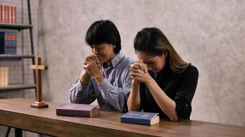 um jovem casal cristão asiático orando a jesus cristo em uma igreja. foto