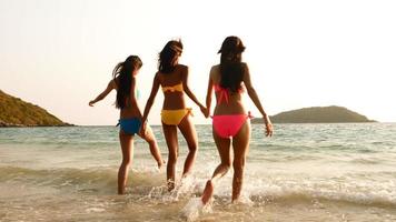 três mulheres sensuais caminhando juntos no mar. foto