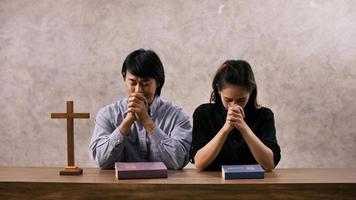 um jovem casal cristão asiático orando a jesus cristo em uma igreja. foto