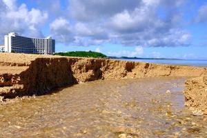 água esculpe um caminho através da areia no resort de praia foto