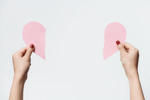 Feche as mulheres segurando papel em branco rosa com forma de coração em fundo branco. foto