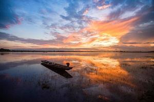 silhueta barco de pesca lago lindo céu com velho barco de pesca de madeira pôr do sol no rio nascer ou pôr do sol foto