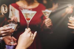 foto recortada de mulheres irreconhecíveis bebem coquetéis alcoólicos, passam o tempo livre na boate, comemoram algo. bebida alcoólica nas mãos das mulheres. amigos tocam copos com coquetel