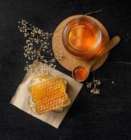 favo de mel com concha de mel e flor seca em fundo preto, produtos apícolas pelo conceito de ingredientes naturais orgânicos foto