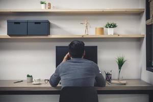 jovem freelancer masculino com computador na sala, homem trabalhando na mesa, artista freelance criativo foto