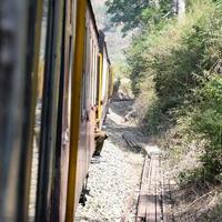 trem de brinquedo movendo-se nas encostas das montanhas, bela vista, uma montanha lateral, um vale lateral movendo-se na ferrovia para a colina, entre a floresta natural verde. trem de brinquedo de kalka para shimla na índia, trem indiano foto