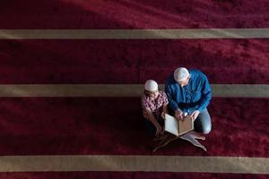 oração muçulmana pai e filho na mesquita orando e lendo o livro de azevinho alcorão juntos conceito de educação islâmica foto