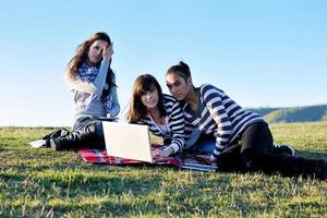 grupo de adolescentes trabalhando no laptop ao ar livre foto