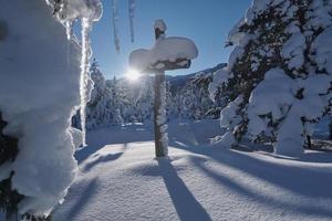 cruz de madeira coberta de neve fresca na bela manhã de inverno fresco foto