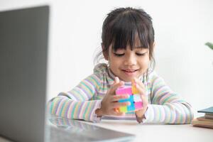 nakhon ratchasima tailândia 14 de julho de 2022 menina bonitinha asiática segurando o cubo de rubik nas mãos. cubo de rubik é um jogo que aumenta a inteligência das crianças. foto