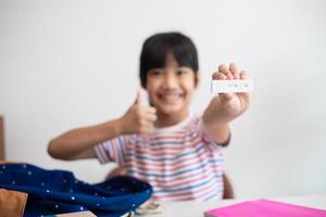 menina asiática é testada para covid-19 antes da aula. foto