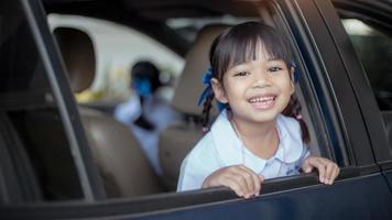 garota estudante asiática pronta para ir para a escola e acenando adeus ou dizer oi no fundo do carro. de volta ao conceito de escola. foto