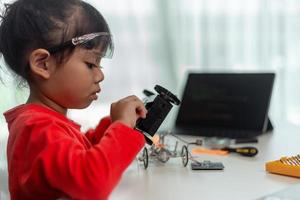 os alunos da ásia aprendem em casa na codificação de carros robóticos e cabos de placa eletrônica em haste, vapor, código de computador de tecnologia de ciência de engenharia matemática em robótica para o conceito de crianças. foto