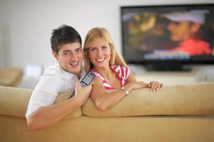 jovem casal relaxado assistindo tv em casa foto