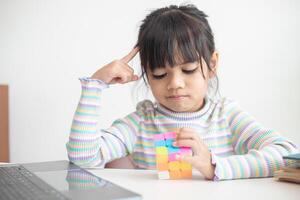 menina bonitinha asiática segurando o cubo de rubik nas mãos dela. cubo de rubik é um jogo que aumenta a inteligência das crianças. foto