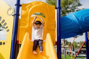 garotinha descendo o escorregador ao ar livre no parque ou playground foto