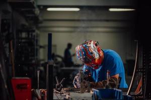 soldador profissional da indústria pesada trabalhando dentro da fábrica, usa capacete e começa a soldar. foco seletivo foto