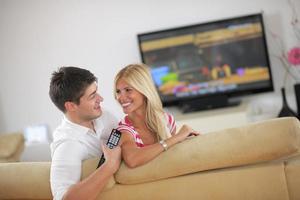 jovem casal relaxado assistindo tv em casa foto