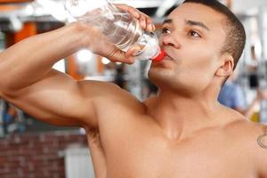 homem bebendo água no ginásio de esporte