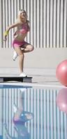 exercício de fitness mulher à beira da piscina foto