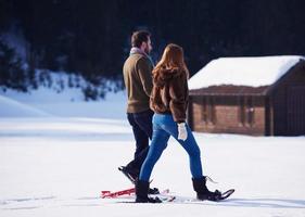 casal se divertindo e andando com sapatos de neve foto