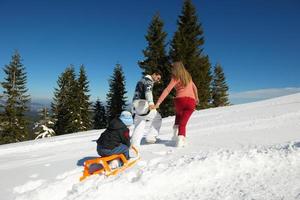 família se divertindo na neve fresca no inverno foto