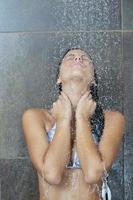 sexy jovem desfrutando de banho sob o chuveiro de água foto