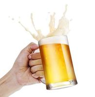 mão segurando uma caneca de cerveja light brindando com respingo de espuma de bolha isolar fundo branco com espaço de cópia foto