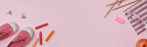 flatlay criativo de mesa de educação rosa com livros de estudante, sapatos, giz de cera colorido, óculos, espaço vazio em estúdio tiro isolado no fundo de banner longo rosa, conceito de educação foto