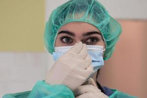 a cirurgiã ou veterinária de animais femininos coloca uma máscara facial médica. médico está se preparando para a cirurgia na sala de operação. medicina e saúde foto