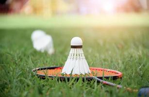 raquete de badminton e peteca de badminton contra um fundo nublado e azul, conceito de jogo de badminton ao ar livre. foco seletivo na raquete. foto