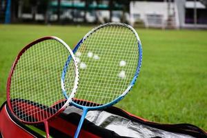 raquete de badminton e peteca de badminton contra fundo nublado e azul, conceito de jogo de badminton ao ar livre. foco seletivo na raquete. foto