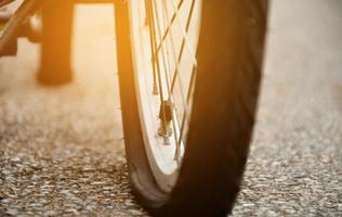 roda plana traseira closeup de bicicleta vintage no pavimento à noite do dia, luz do sol editada, foco suave e seletivo foto