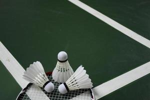 petecas e raquetes de badminton branco creme no chão verde na quadra de badminton coberta foto