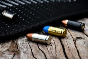 Balas de pistola de 9 mm e conchas de bala na mesa de madeira, foco suave e seletivo. foto