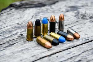 Balas de pistola de 9 mm e conchas de bala na mesa de madeira, foco suave e seletivo. foto