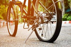 closeup vista da roda traseira da bicicleta velha que é plana e estacionada na calçada no parque público, foco suave e seletivo. foto