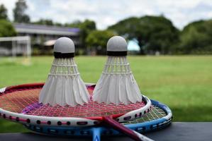 raquete de badminton e peteca de badminton contra fundo nublado e azul, conceito de jogo de badminton ao ar livre. foco seletivo na raquete. foto