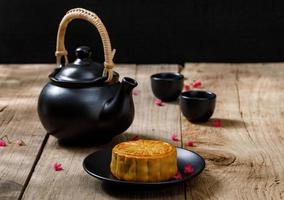 bolo de lua de comida deliciosa com uma xícara de chá quente no fundo da mesa de madeira com copyspace para o seu texto, conceito de festival tradicional chinês foto