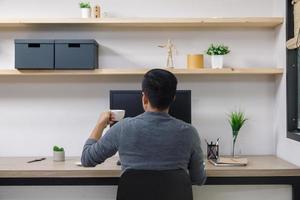 jovem freelancer masculino com computador na sala, homem trabalhando na mesa, artista freelance criativo foto