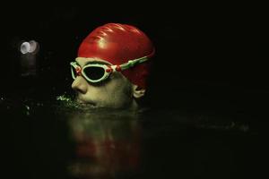 nadador de triatleta autêntico fazendo uma pausa durante o treinamento duro na luz de néon de gel noturno foto